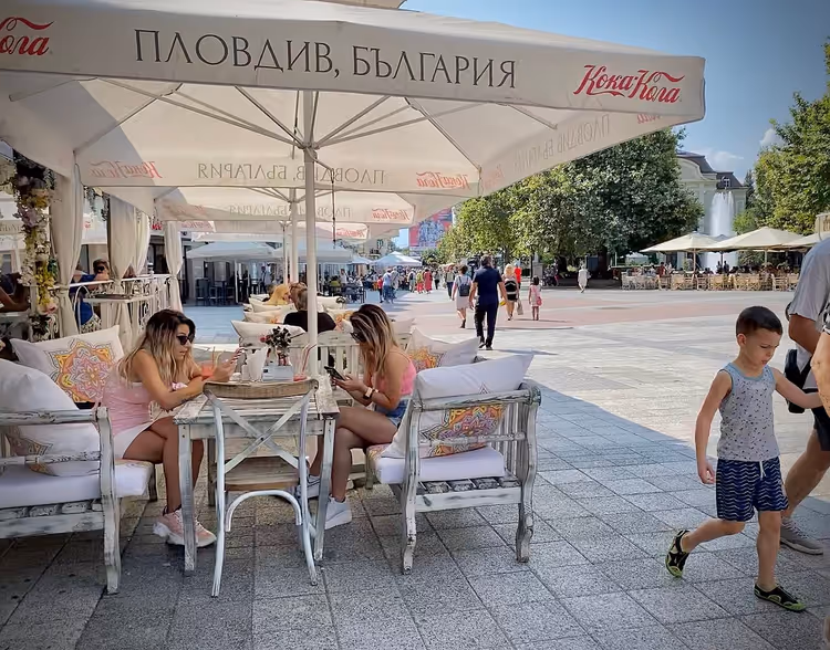 Mensen aan tafeltjes op een terras in Plovdiv