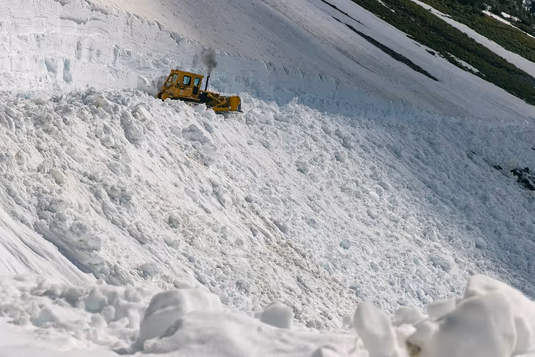 Pistenraupe räumt eine tiefe Schneewehe an einem Hang