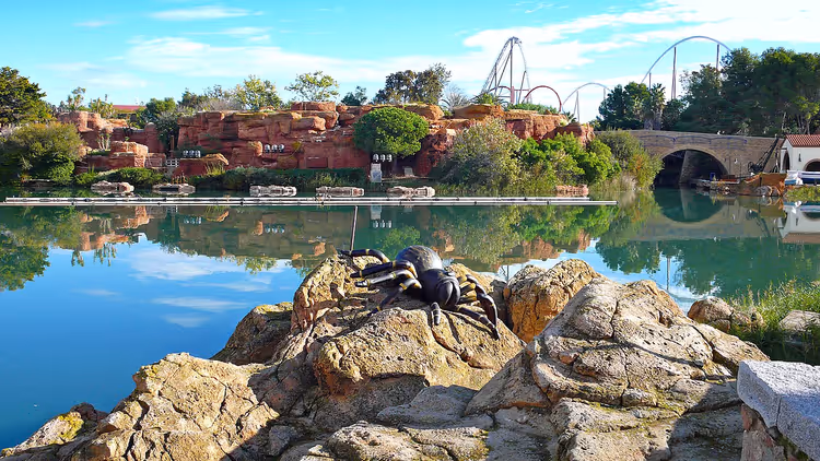 PortAventura'da arka planda göl ve hız trenleri olan örümcek heykeli