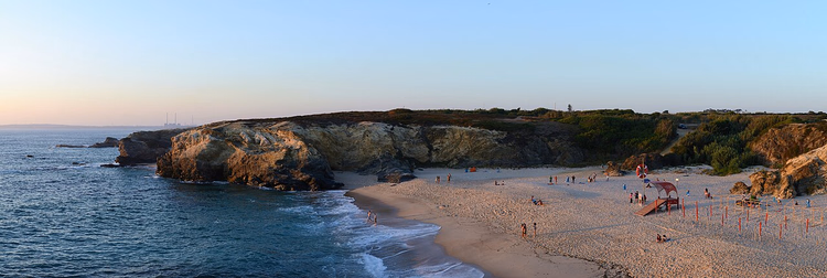 Gün batımında Porto Covo'nun kayaları arasında kumlu plaj