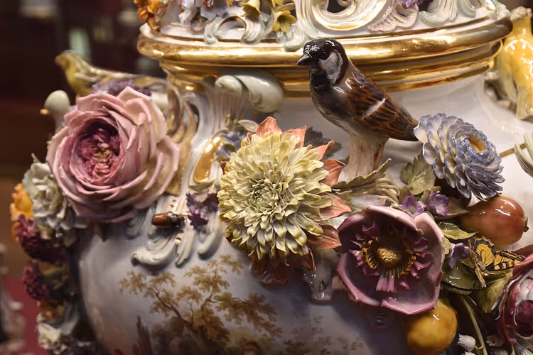 Porseleinen vaas met opgelegde bloemen en een vogel