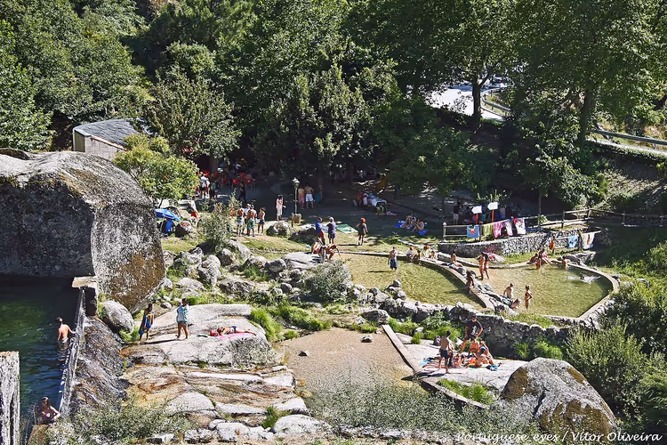 Mensen ontspannen op een rivierstrand tussen rotsen en bomen