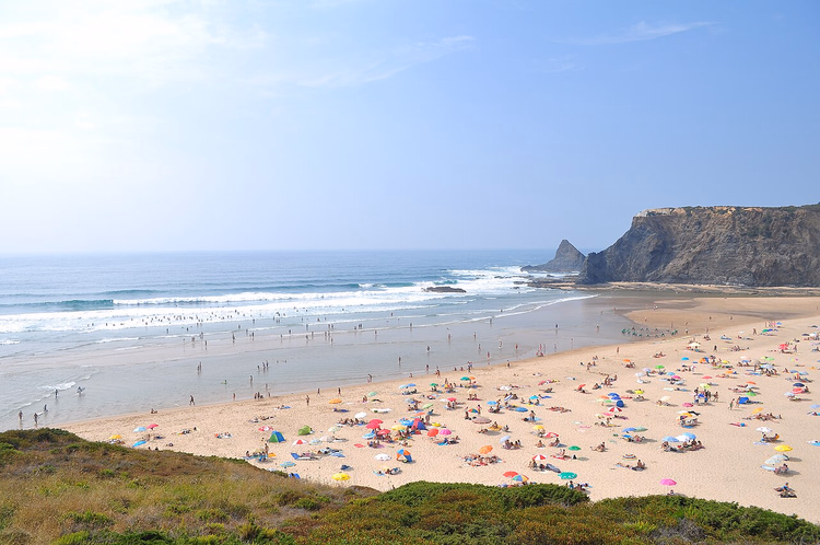 Sandstrand von Odeceixe mit Steilküste und Badegästen