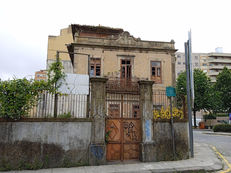 Gammel herskapsbolig bak et gjerde i en gate i Porto