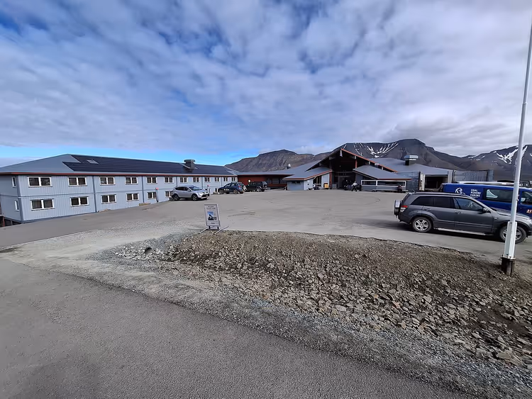 Hotellbygg med parkering og fjell i Longyearbyen
