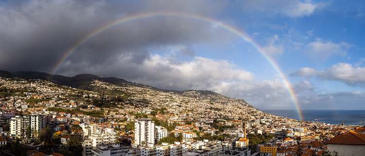 Panorama av Funchal med en regnbue over byen og havet