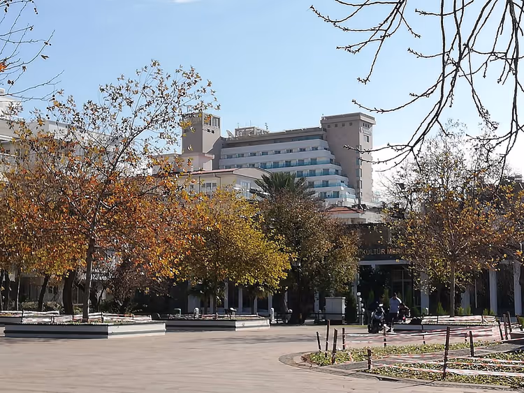 Hoogbouw Ramada Plaza hotel achter bomen aan het plein