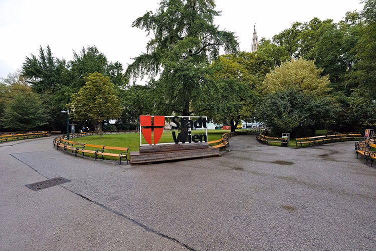 Stadt Wien-skiltet i parken, rådhustårnet bak trærne
