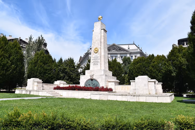 Witte obelisk met een gouden ster tussen het groen