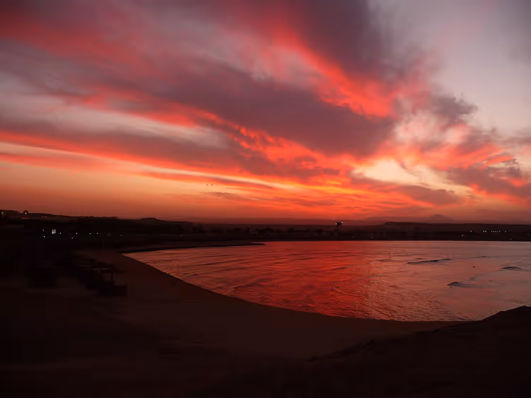 Rode zonsondergang boven de zee en het strand
