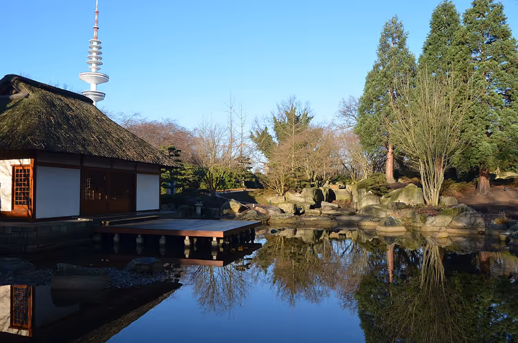 Japansk hage med en dam og et tehus speilet i vannet