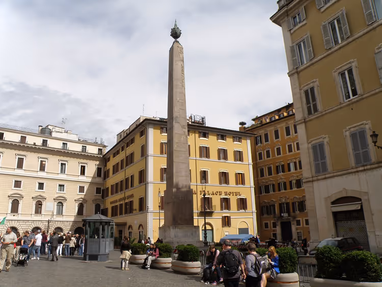 Obelisco com uma cruz numa praça entre edifícios em Roma