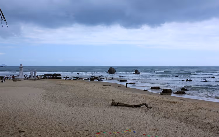 Zandstrand, zee, wolken, mensen en een witte toren
