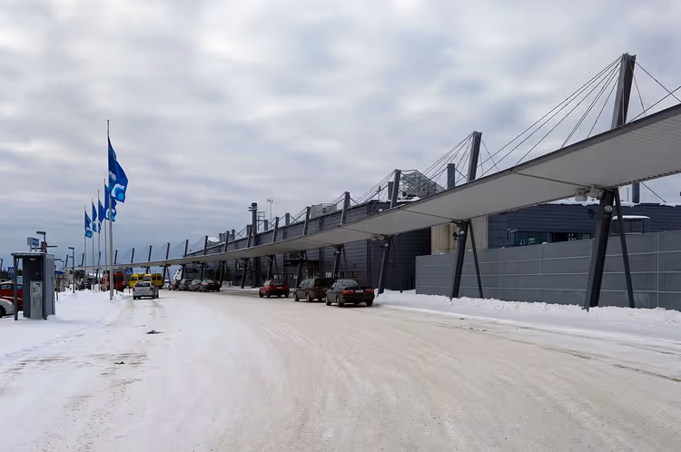 Besneeuwde ingang van de terminal van Rovaniemi Airport met een luifel