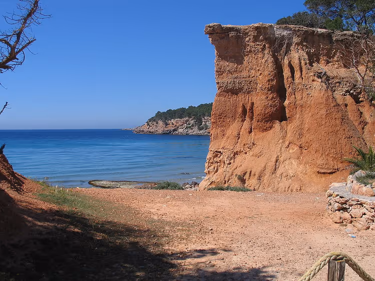 Deniz kenarında kızıl kayalık ve Sa Caleta koyu
