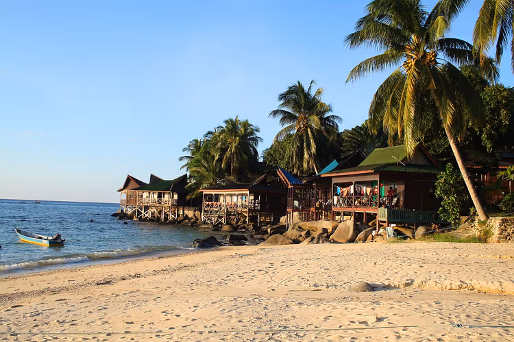 Tropisch strand met bungalows en palmbomen