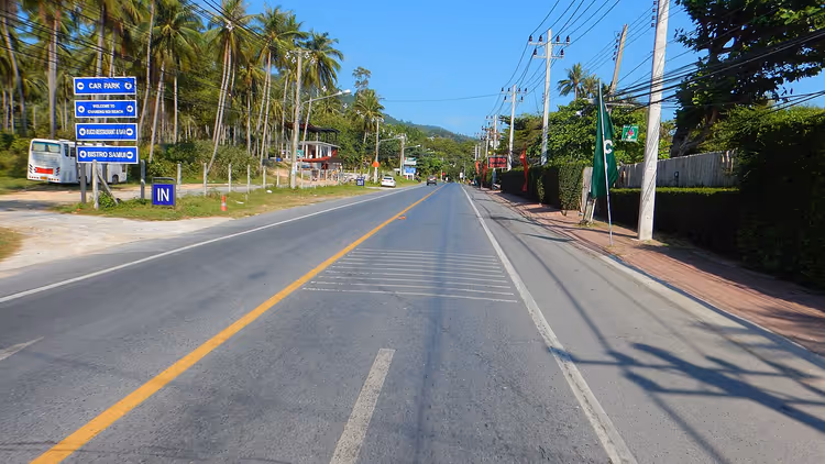 Veien med palmer og skilt på Samui