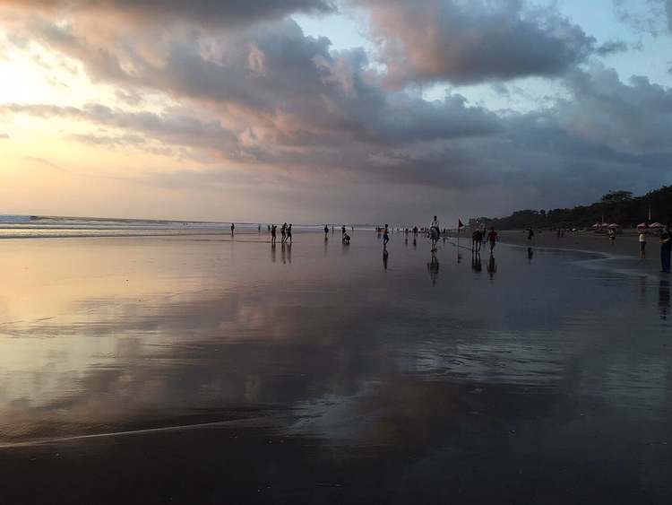 Seminyak Beach bij zonsondergang, surfers dicht bij het water