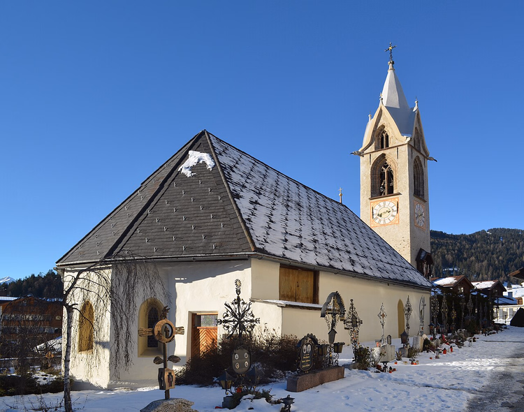 Kirche mit Glockenturm im verschneiten Dorf Serfaus