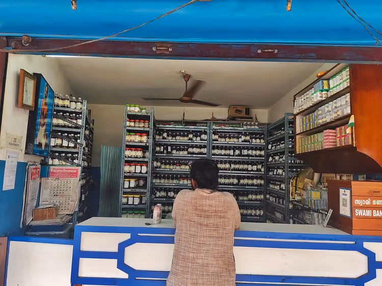 Ayurvedische apotheek met schappen vol medicijnen en een bezoeker