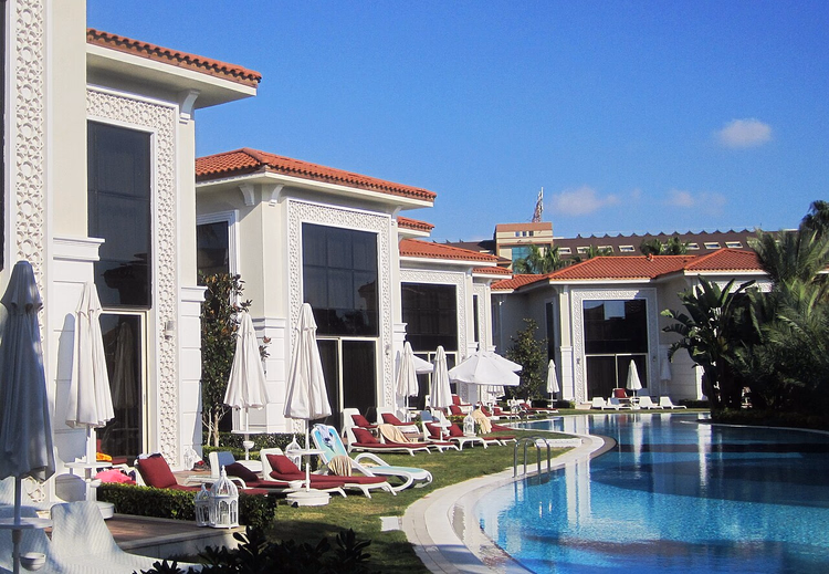 Şezlonglarla havuz kenarındaki otel villaları