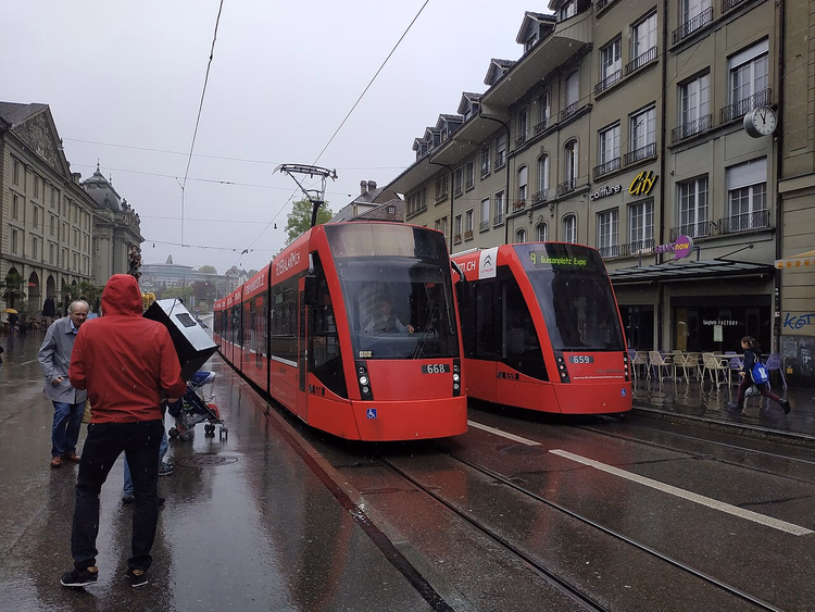 Røde trikker i en regnvåt gate i Bern
