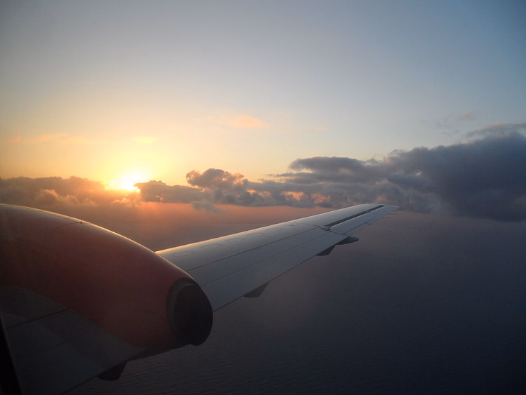 Utsikt fra flyvinduet av vingen i solnedgang
