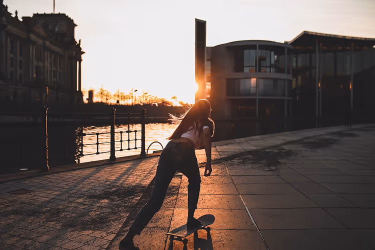 Kvinnelig skater på Berlins elvebredd ved solnedgang