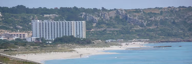 Wit hoogbouw­hotel achter het strand van Son Bou