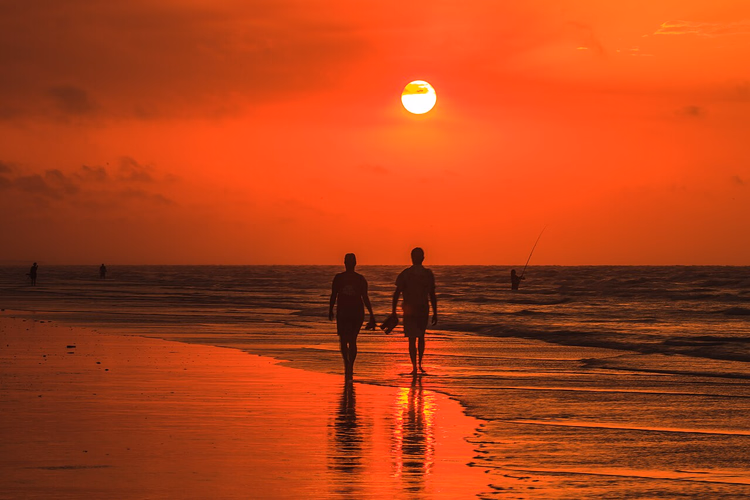 Par som går på stranden i solnedgang
