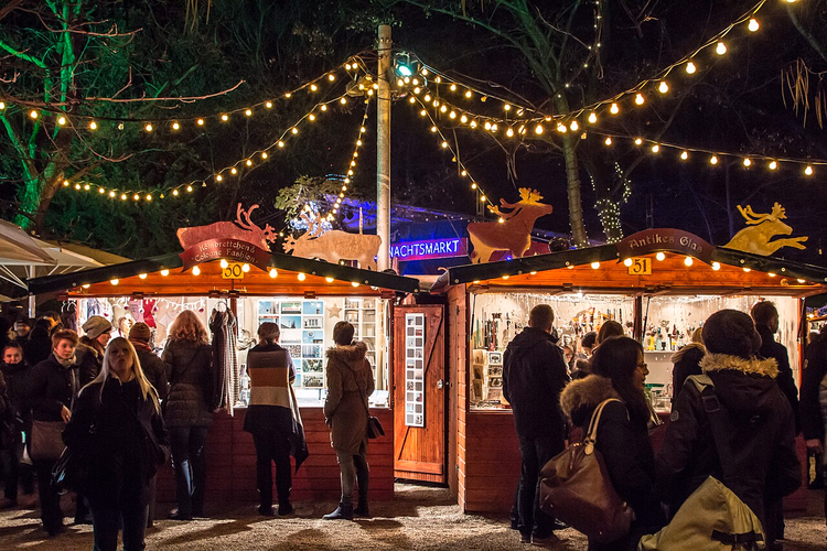 Hölzerne Weihnachtsmarktbuden mit Lichterketten im Park
