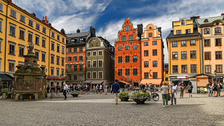 Bunte Fassaden und ein Brunnen am Stortorget im Sommer