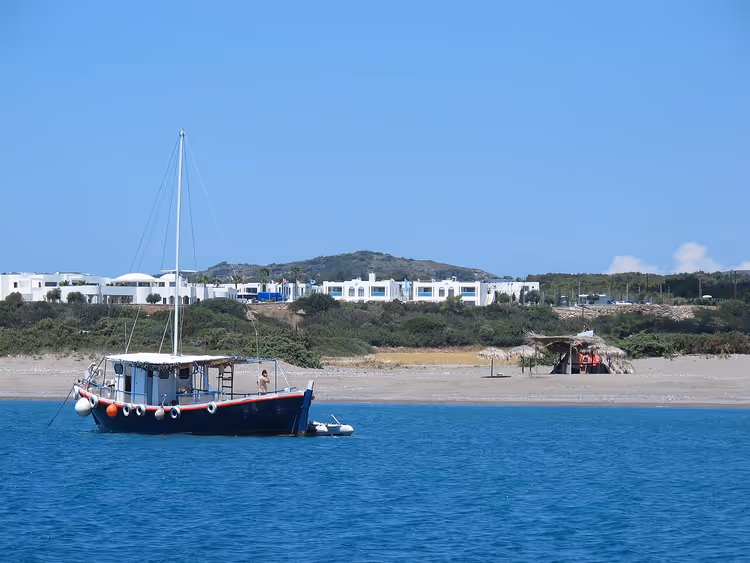Bir tekne ve beyaz otel binalarıyla Plimmyri Plajı