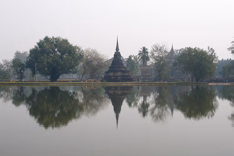 Teich, der eine Stupa im Geschichtspark Sukhothai spiegelt