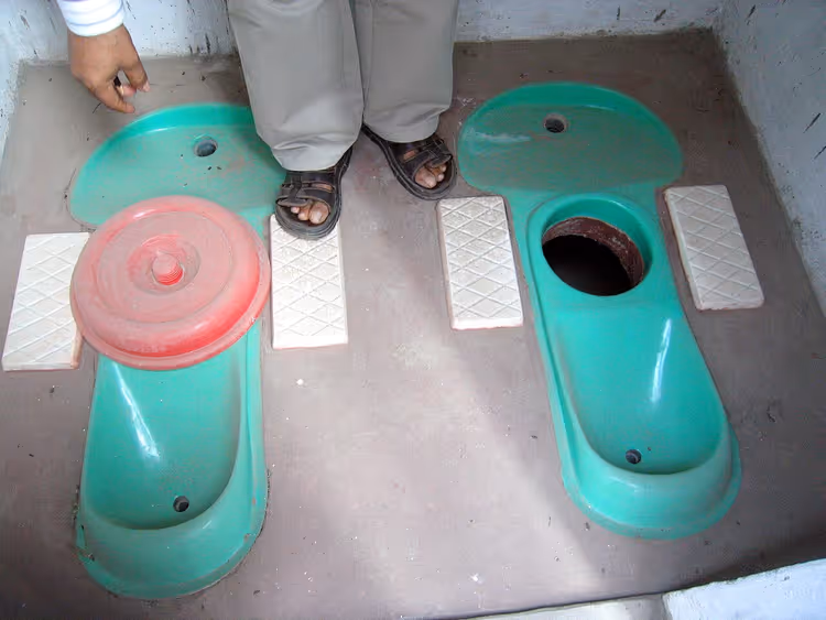 Twee groene Sulabh ecotoiletten met een persoon