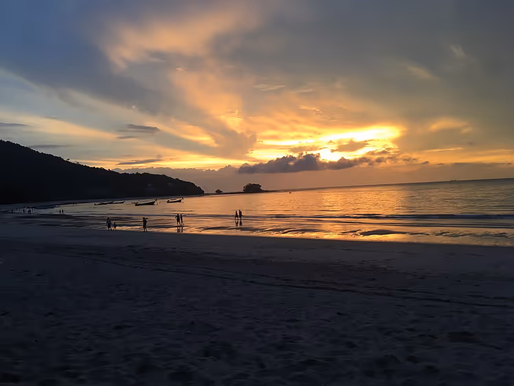 Nai Yang-stranden ved solnedgang med silhuetter av mennesker