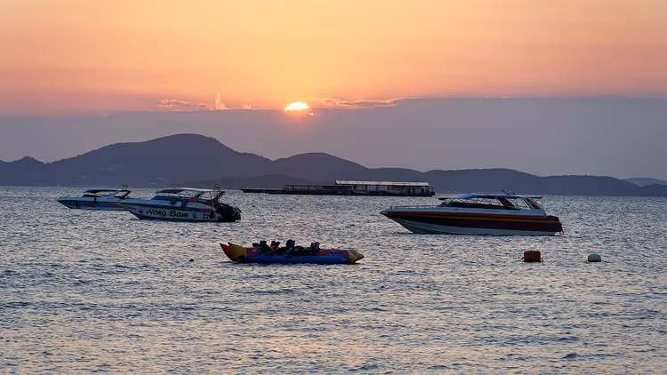 Zonsondergang boven zee met boten voor de kust