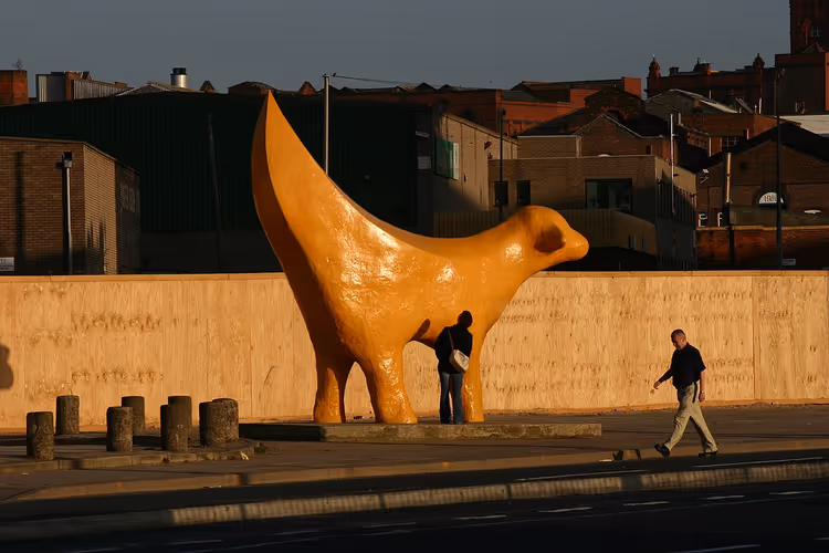 Gul Superlambanana-skulptur i en gate med fotgjengere