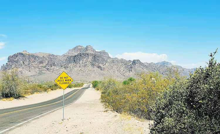 Superstition Mountains achter een woestijnweg met een bord