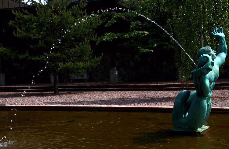 Bronzen triton met waterstraal in een bassin