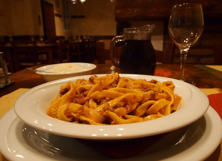 Tagliatelle mit Ragù und eine Karaffe Wein in einer Trattoria