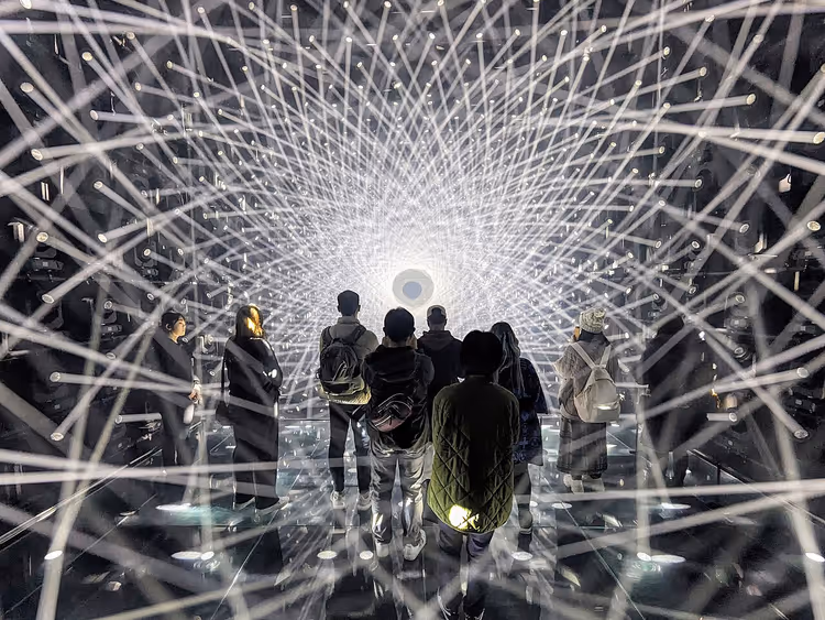 Besøkende i en lysinstallasjon på teamLab Borderless med en kule