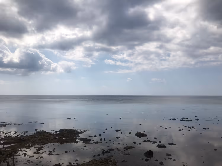 سماء غائمة فوق البحر وشاطئ صخري