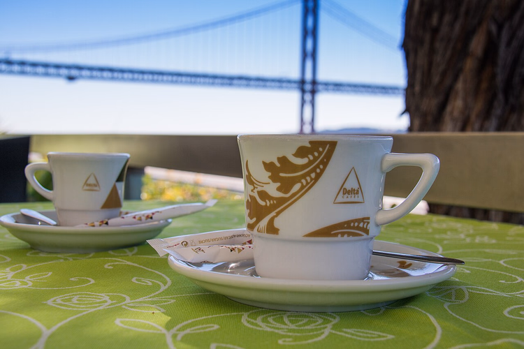 Delta-koffiekopjes met de Lissabonse brug op de achtergrond