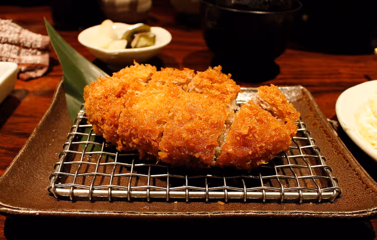 Geschnittenes, frittiertes Schweineschnitzel Tonkatsu auf einem Gitterrost