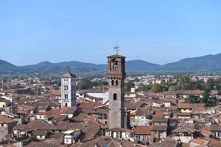 Klokketårn i tegl over de teglsteinsbelagte takene i Lucca