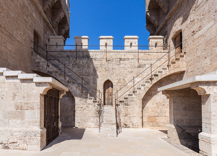Escadarias de pedra e ameias entre as torres da Porta de Quart