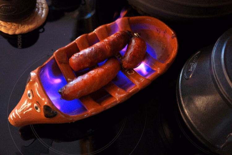 Chouriço-Würste, die in einem Tonröster grillen