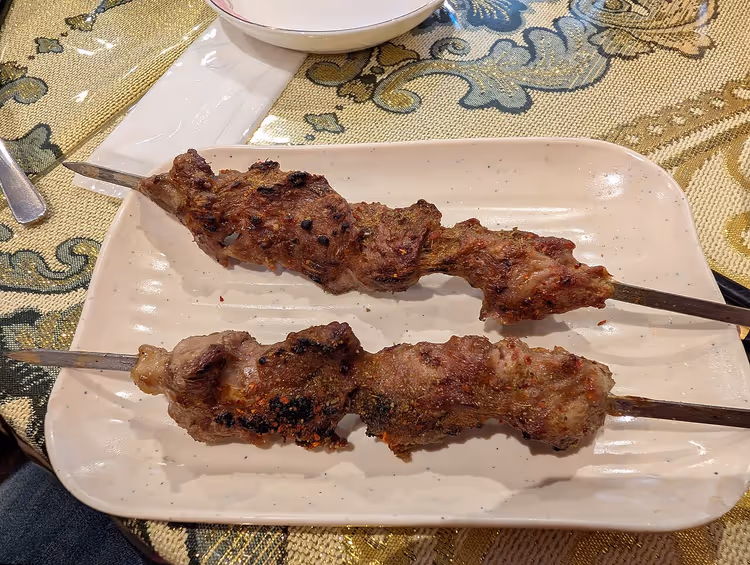 Kaksi varrasta, joissa on grillattua kebablihaa lautasella