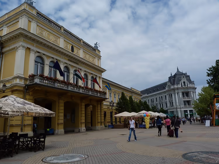 Жёлтое здание ратуши с флагами на площади